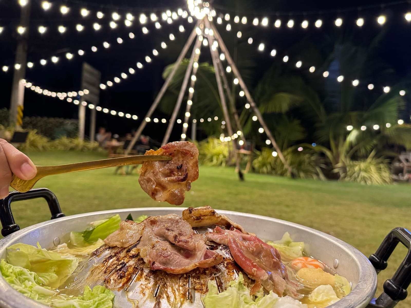 หมูกระทะบนเตา ใต้แนวไฟสายยามค่ำคืนที่ร้านแค้มป์ปังปิ้ง